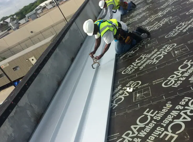 Armored roofer fitting a metal gutter on a commercial roof